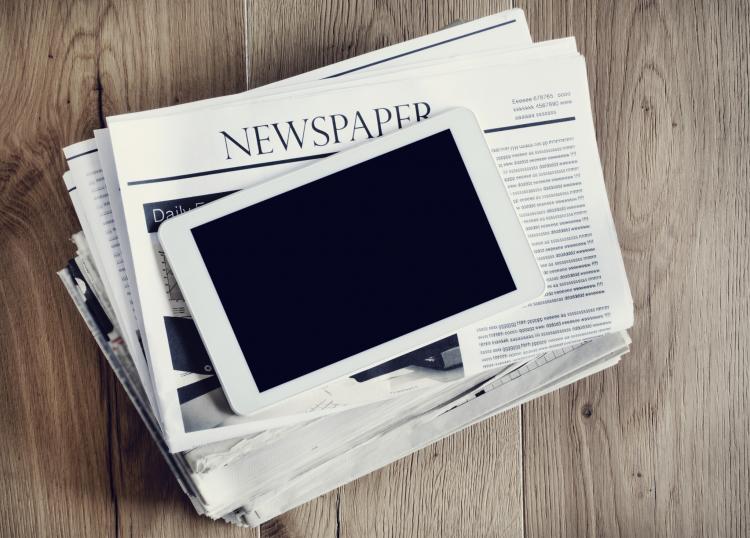 Computer tablet on newspaper stack