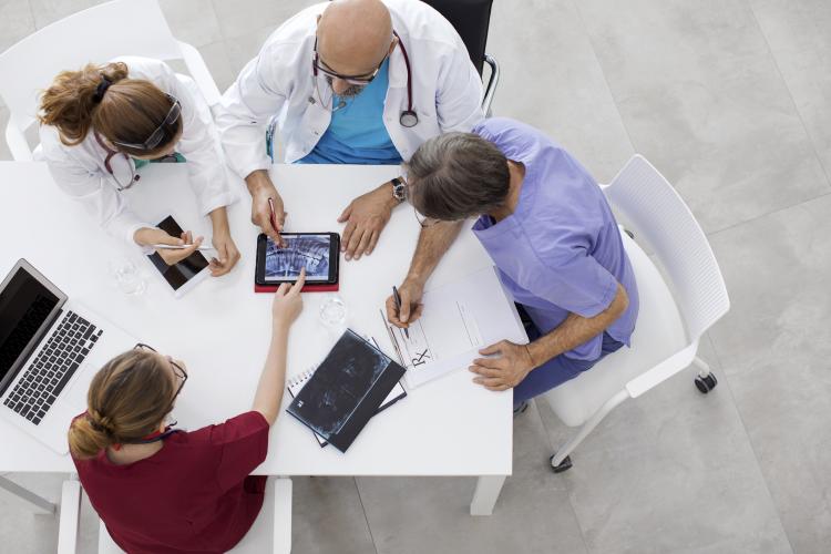 Nurses and doctors gather around a tablet and laptop
