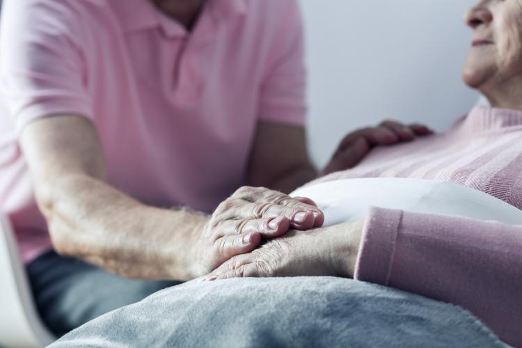 nurse holds hand of patient in hospital bed